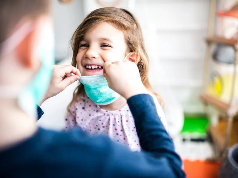 A happy little girl wearing a face mask.