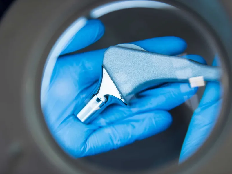 A surgeon holding an ortho tool under a magnifying glass