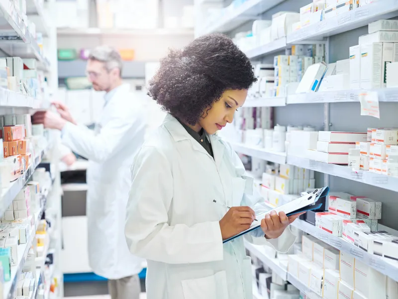 Female and male pharmacist working in an aisle in a pharmacy.