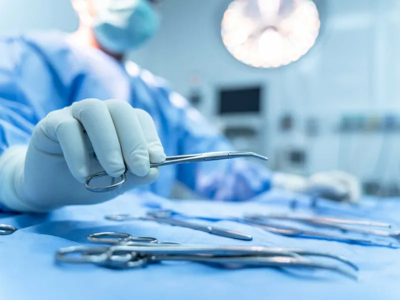 A surgeon picking up a pair of surgical scissors