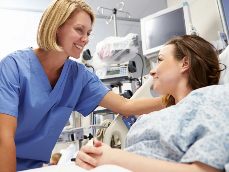 A woman on her hospital bed talks with her doctor.