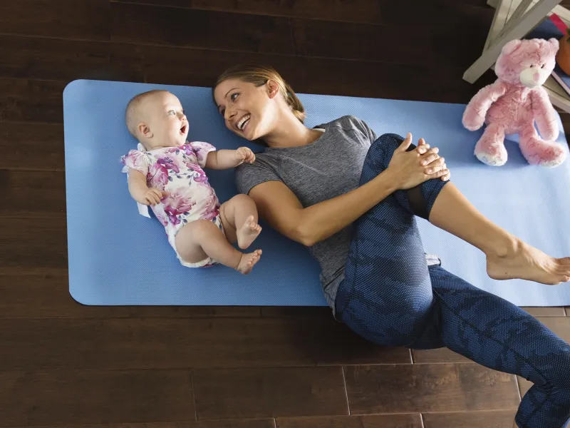 A young mother plays on the floor with her toddler.