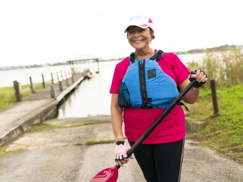 Woman wearing a life vest and holding a boating paddle
