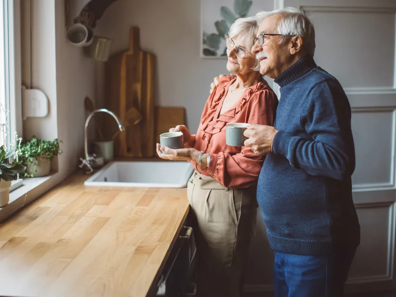 man and woman in kitchen looking out window