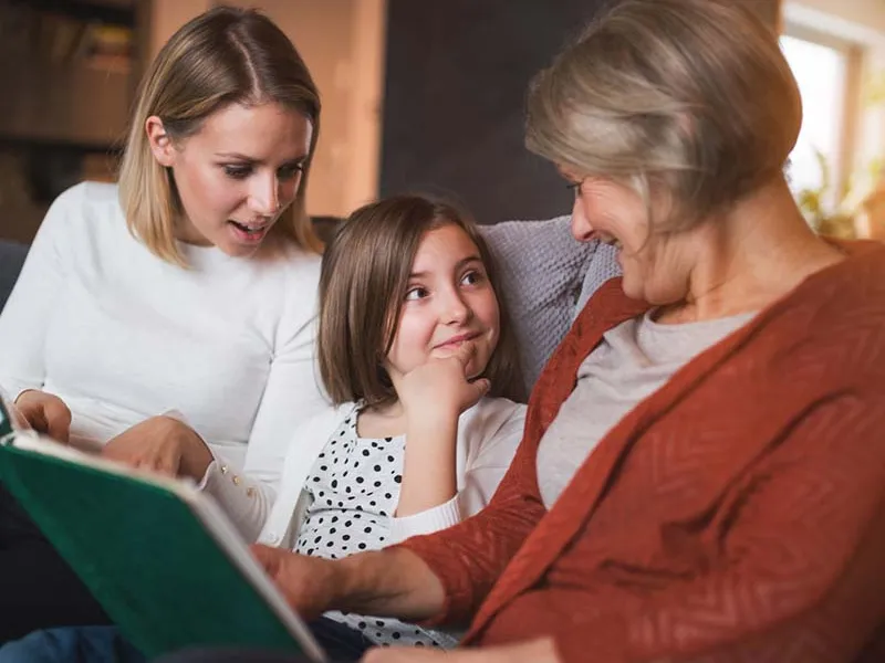 Grandmother mother and girl reading on couch