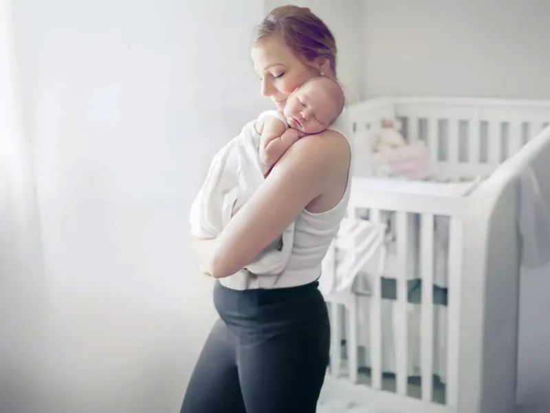 Woman holding baby in home nursery