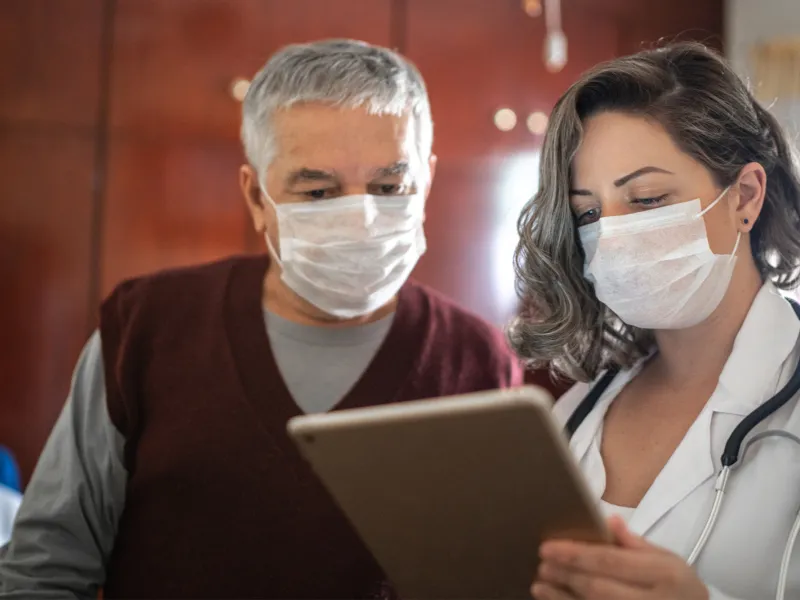 Man looking at chart with a doctor while both are wearing masks.