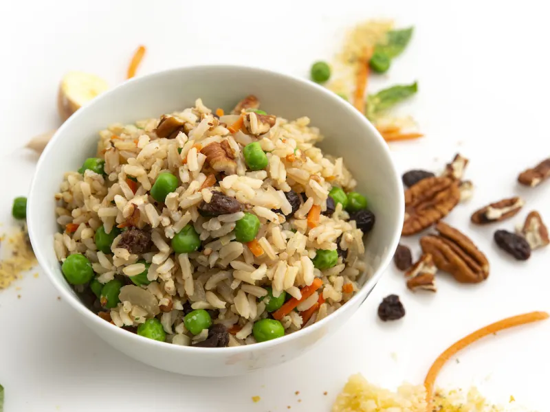 Bowl of pilaf on white counter with pecan garnish