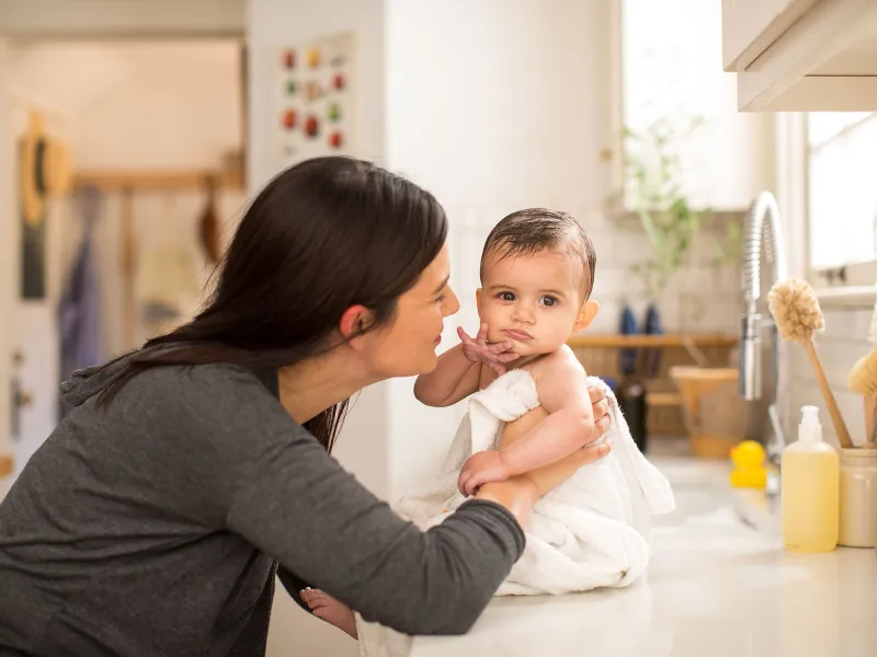 A mom drying her baby in the kitchen's counter-top.
