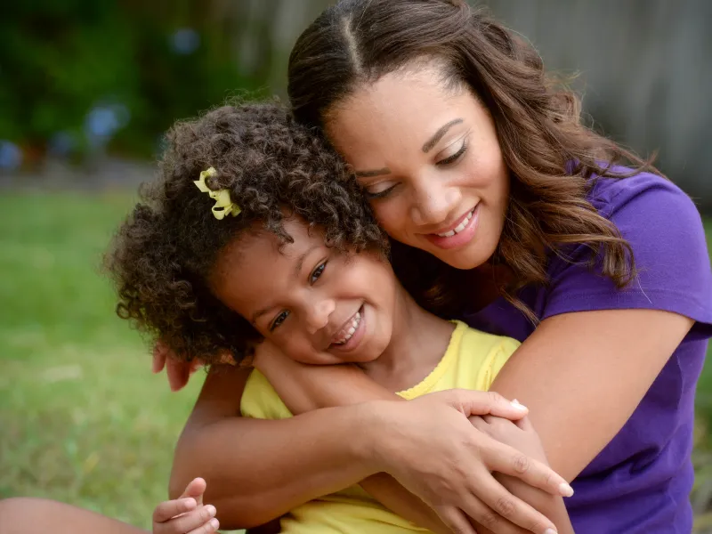 A mother hugs her daughter from behind. 