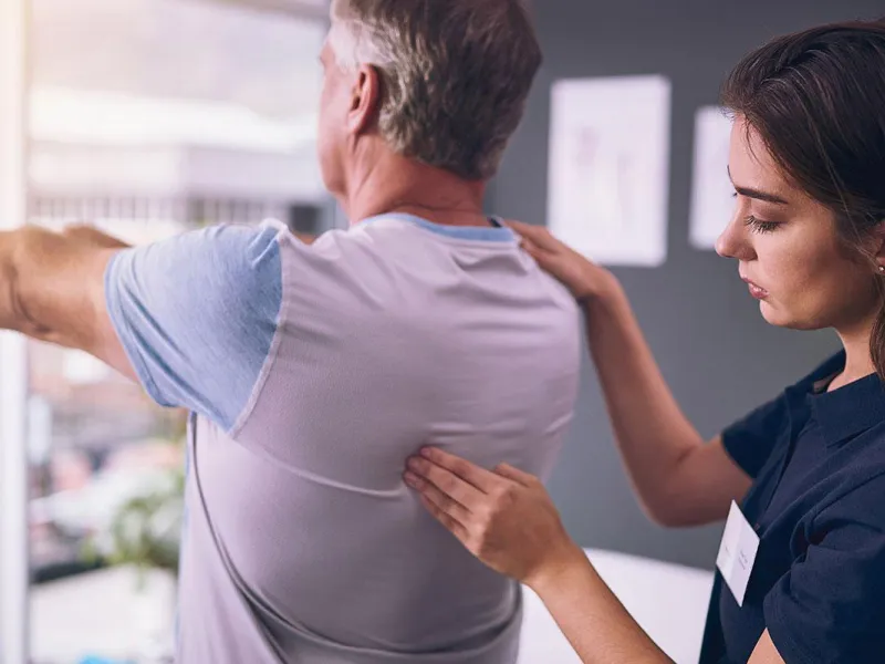 Nurse pressing on back muscle of a rehab patient