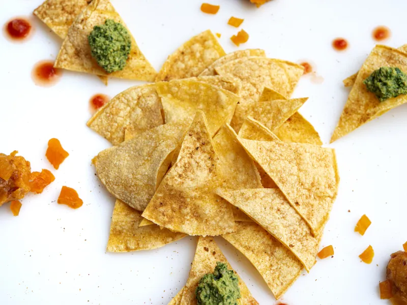 Pile of tortilla chips with salsa and guac.
