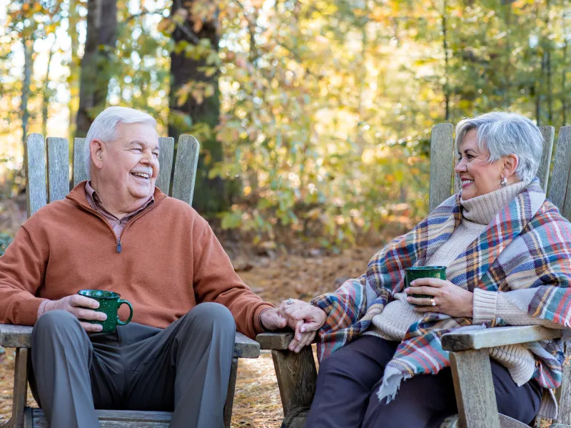 Older man and woman sitting and smiling at each other in the forest