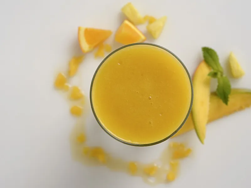 an overhead shot of a clear glass filled with pineapple-mango smoothie