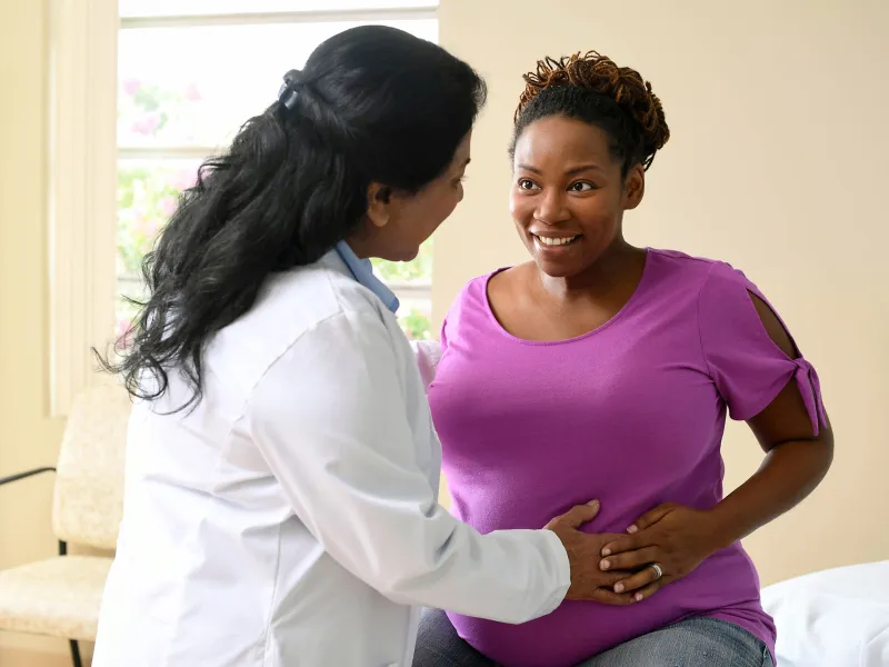 A nurse having a friendly conversation with a patient who is expecting a baby. 