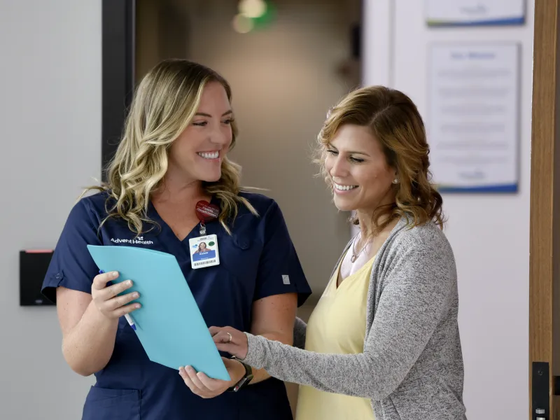 A Primary Care+ Nurse Goes Over Paperwork with a Smiling Patient