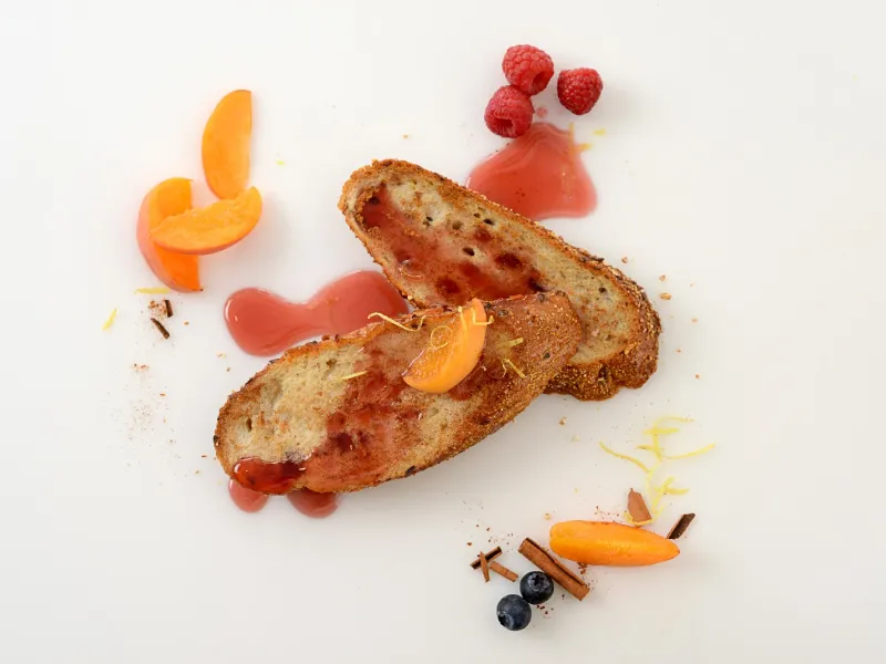 two slices of whole-grain french bread french toast, topped with a fruit sauce 