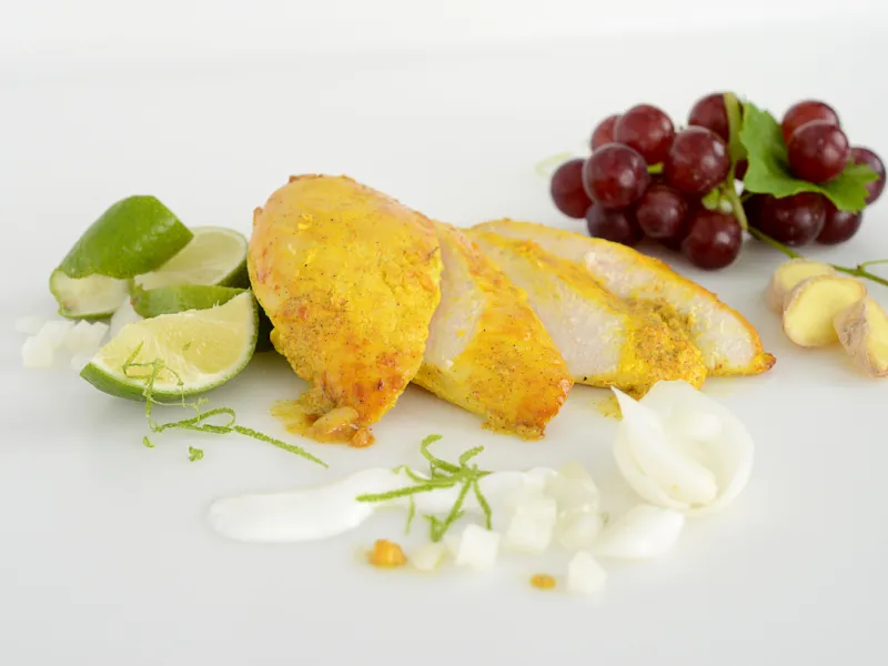 Sliced filet of tandoori chicken with lime and grape garnishes