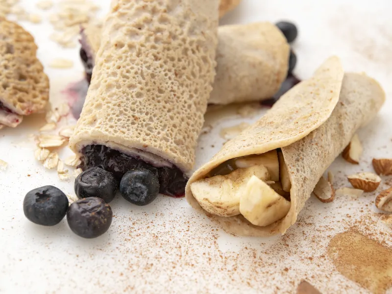 Two crepes filled with blueberries, one crepe filled with potatoes