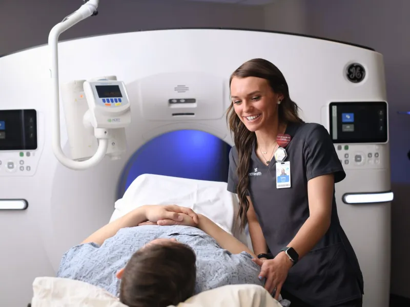 Female imaging technician preparing a male patient for a CT scan.