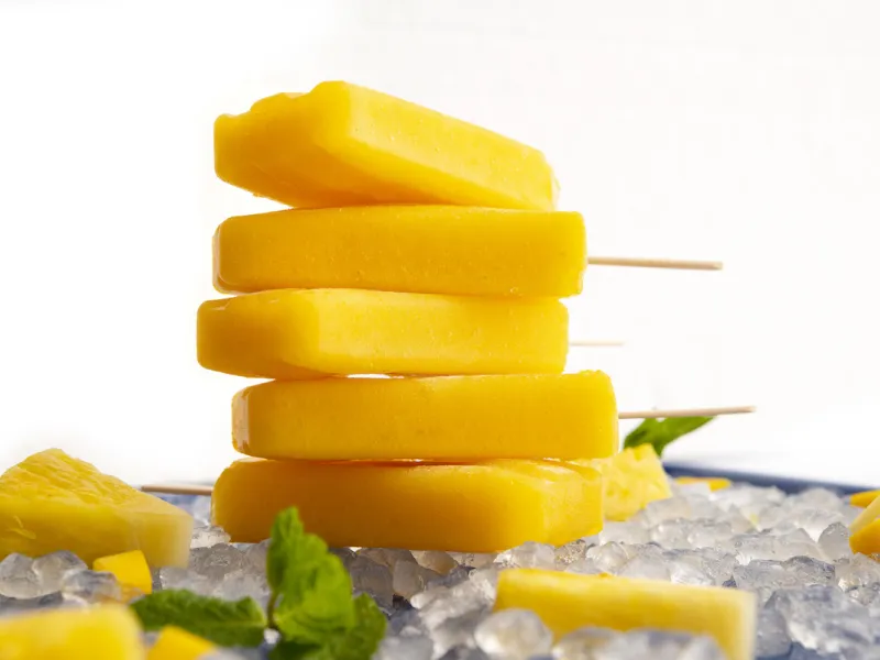 Stack of five orange-colored popsicles on ice