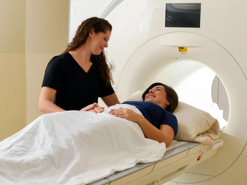 Woman inside medical imaging machine with a nurse standing next to her