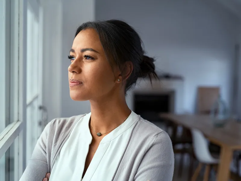 Woman looking out a window while indoors.