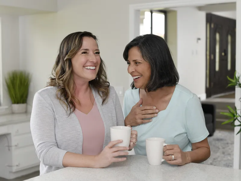 Two women laughing while having coffee together