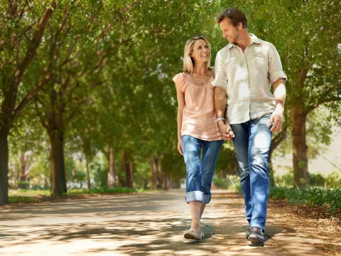Adult couple walking in park lined by trees