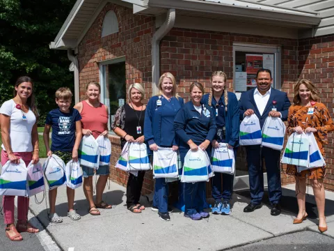 AdventHealth Murray team stands holding backpacks with school supplies