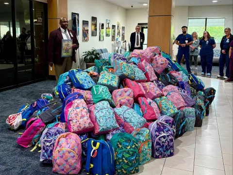 Derrick Hough, AdventHealth DeLand pastoral care chaplain, blesses the backpacks and prepares to pray for the students and teachers.