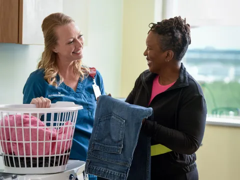 A female patient folds laundry with a rehab specialist.
