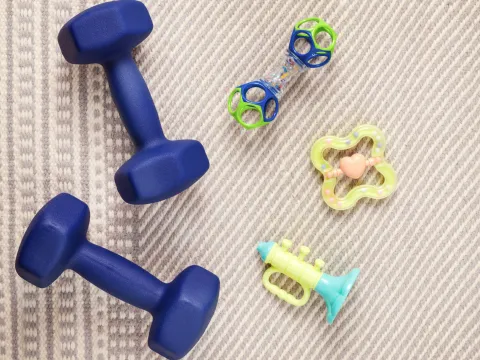 Blue small dumbbells and assorted baby toys on a beige carpet