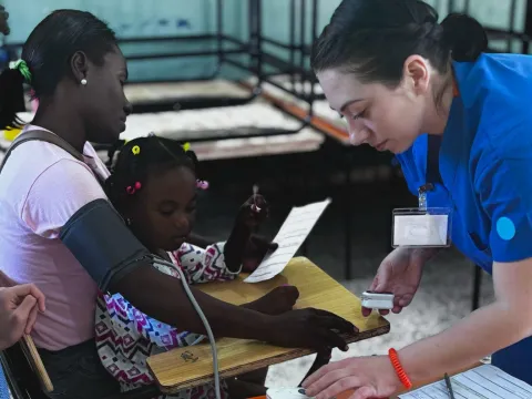 Mission trip worker provides care to woman and girl in Dominican Republic.