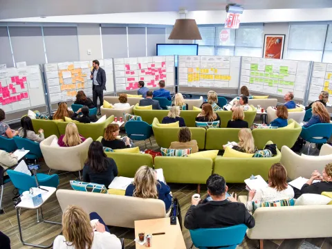 A group meets in a large office space for a strategic meeting.
