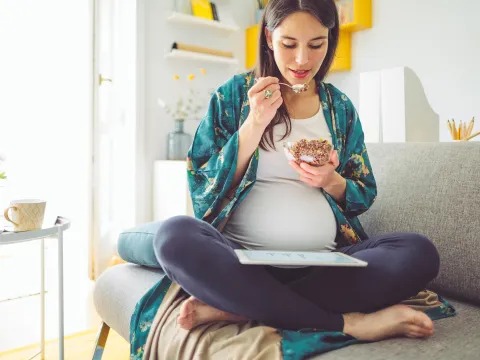A pregnant woman eating breakfast. 