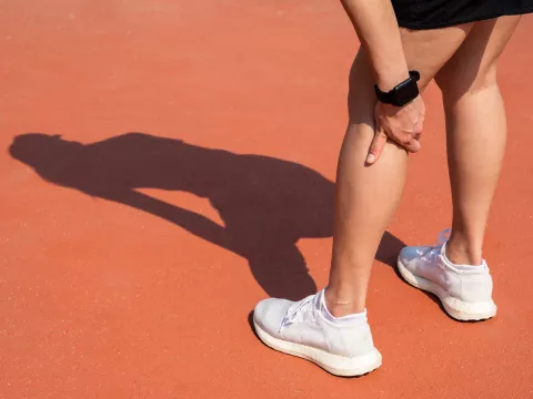 A woman touching her calf, showing concern of injury