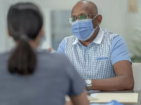 A Health Provider Has a Conversation with a Patient in a Clinic Setting While Wear a Mask