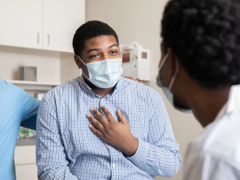 A Man Speaks to His Doctor in a Patient Room While Being Comforted with a Family Member.