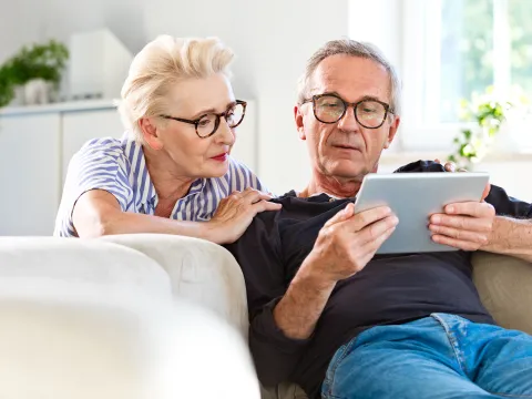 A Senior Couple Reads a Tablet Together in Their Home.