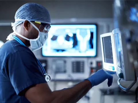 A Doctor Examines a Patient's Information on a Monitor During a Procedure
