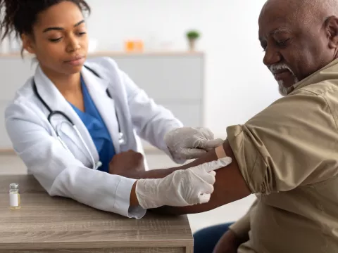 A Physician Puts a Bandage on an Injection Site After a Vaccine