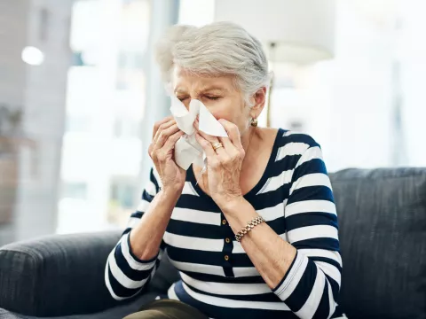 A Senior Woman Blow her Nose with a Tissue