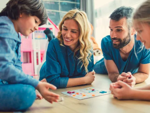 A Family Plays a Board Game Together at Home.
