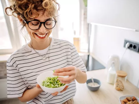 A Woman Smiles as She Mixes a Bowl of Greens