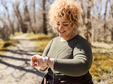 A Woman Checks Her Smart Watch While Going For a Run in the Park