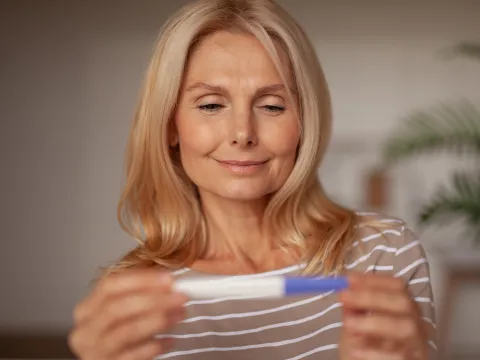 A Woman Smiles as She Looks at a Pregnancy Test