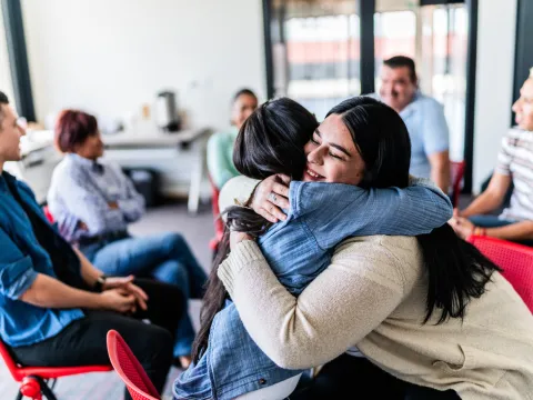 Two People Embrace at a Spiritual Meeting