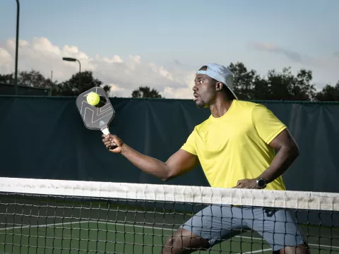 A Man Playing Pickleball on a Tennis Court