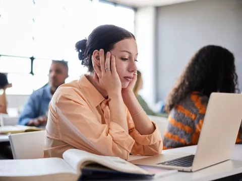 A Woman Holds Her Head In Her Hands as She Tries to Concentrate in a Class